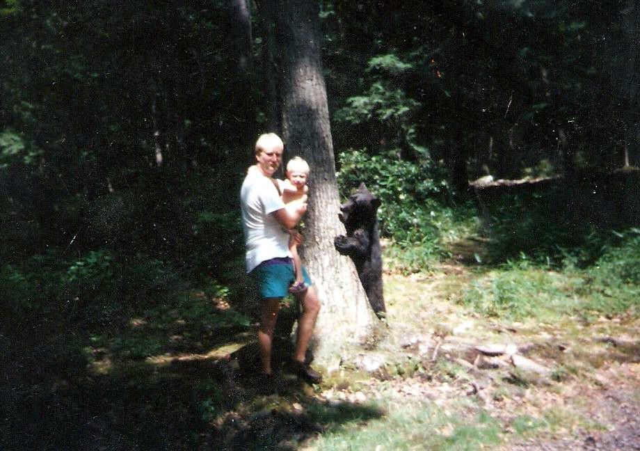 Bear photobombs a family picture of a father and son