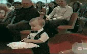 Toddler carrying the wedding rings throws them at the bride and groom.