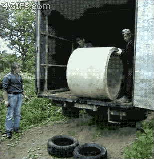 two guys in a truck push a concrete cone onto two tires on the ground and watch as it breaks apart